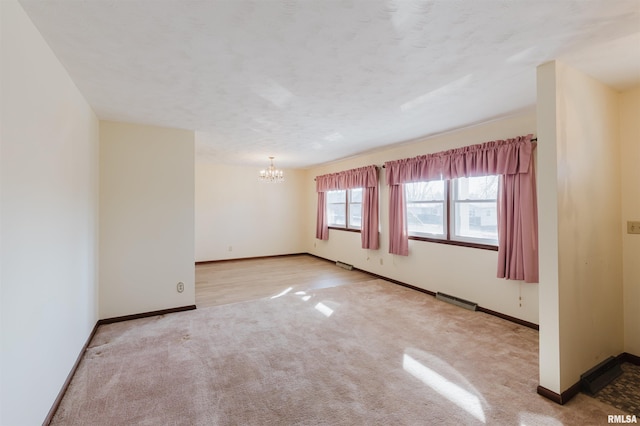 carpeted spare room featuring a textured ceiling and a notable chandelier