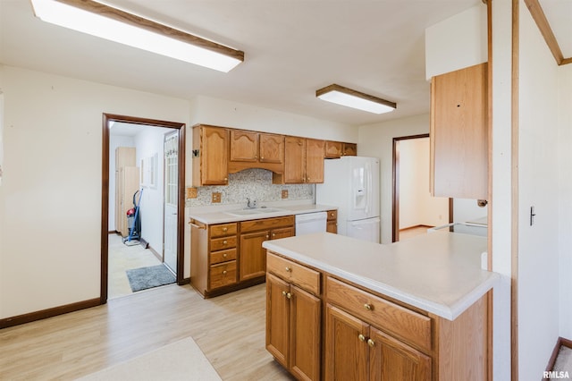 kitchen with white appliances, light hardwood / wood-style floors, sink, and decorative backsplash