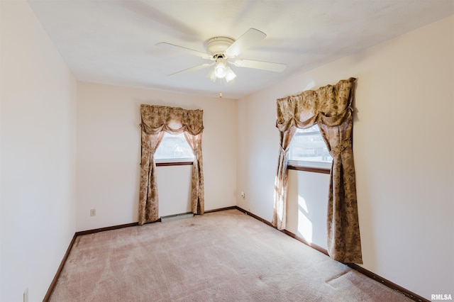 carpeted spare room featuring ceiling fan and plenty of natural light