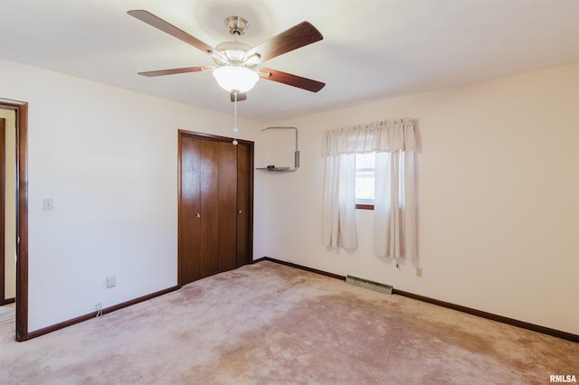 unfurnished bedroom featuring ceiling fan, light carpet, and a closet