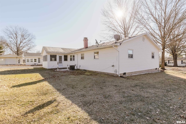 rear view of property featuring a lawn and central air condition unit