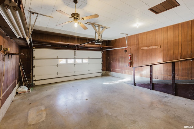 garage with a garage door opener and wood walls