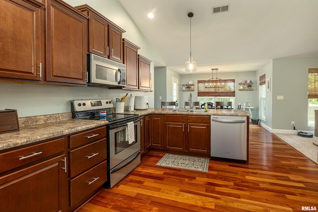 kitchen with pendant lighting, sink, dark hardwood / wood-style flooring, kitchen peninsula, and stainless steel appliances