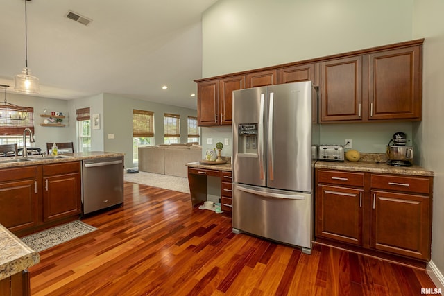 kitchen with appliances with stainless steel finishes, a towering ceiling, dark hardwood / wood-style floors, decorative light fixtures, and sink