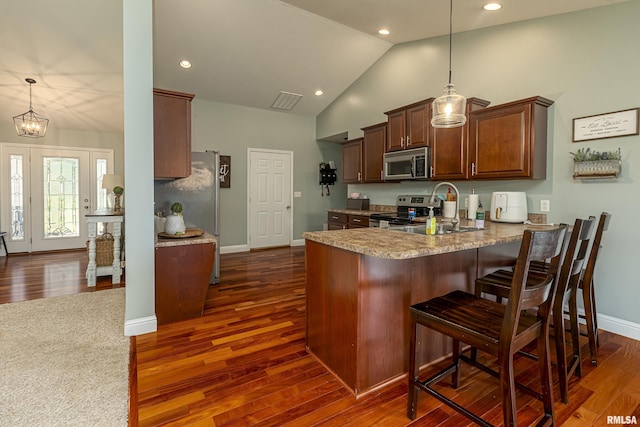 kitchen with pendant lighting, appliances with stainless steel finishes, kitchen peninsula, and sink