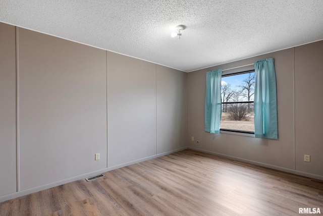 unfurnished room with a textured ceiling and light wood-type flooring