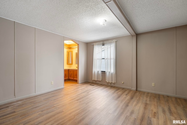 spare room featuring light hardwood / wood-style floors and a textured ceiling