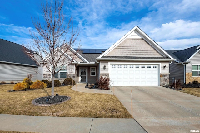 craftsman-style house featuring a garage, a front yard, and solar panels