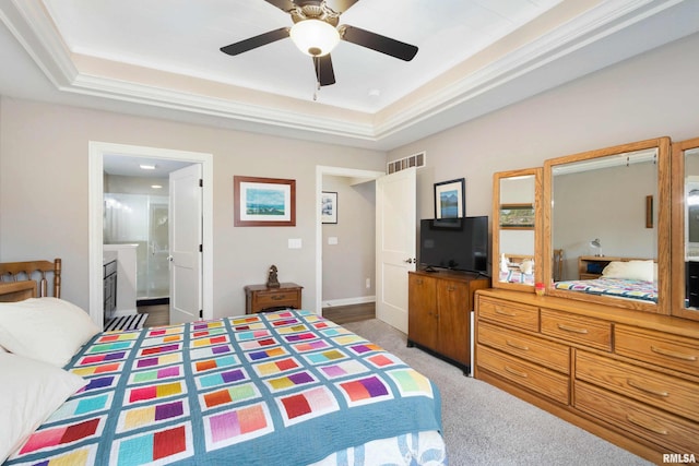 carpeted bedroom featuring a raised ceiling, connected bathroom, and ceiling fan