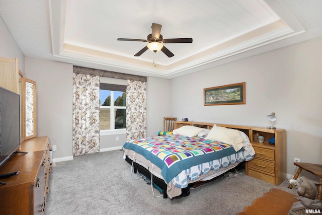 carpeted bedroom featuring ceiling fan and a tray ceiling