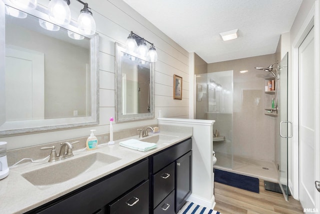 bathroom with hardwood / wood-style flooring, vanity, walk in shower, toilet, and a textured ceiling