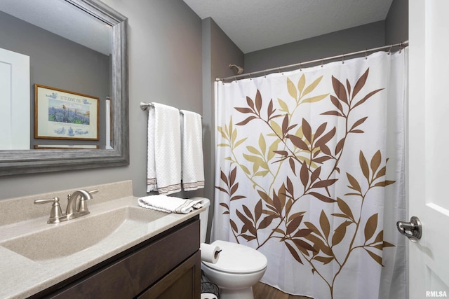 bathroom featuring vanity, toilet, a shower with shower curtain, and a textured ceiling