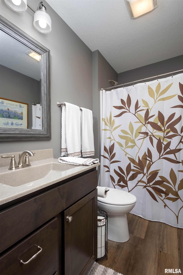 bathroom featuring vanity, hardwood / wood-style floors, a textured ceiling, and toilet