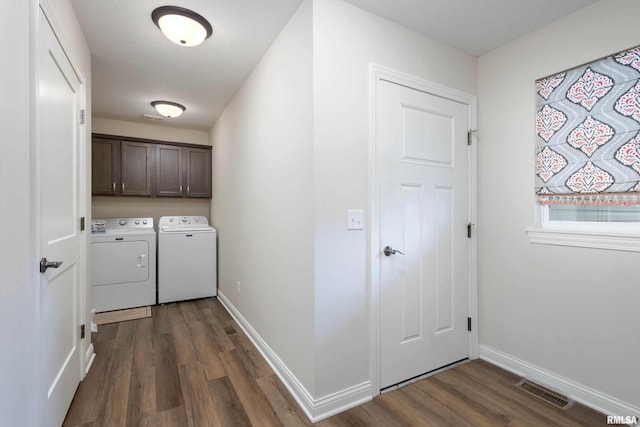 clothes washing area with dark wood-type flooring, cabinets, and washing machine and clothes dryer