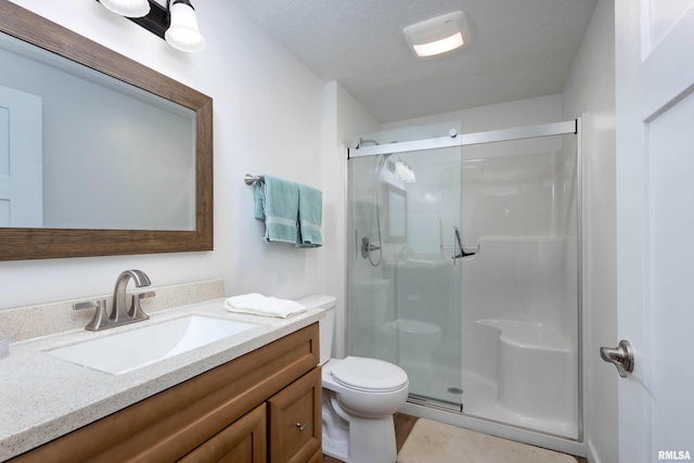 bathroom with vanity, a textured ceiling, toilet, and walk in shower