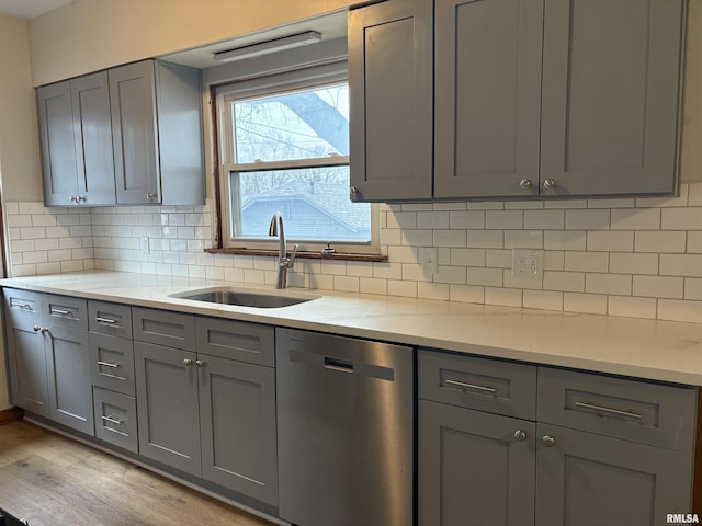 kitchen featuring gray cabinetry, sink, and stainless steel dishwasher