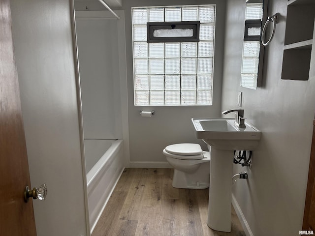 bathroom featuring wood-type flooring, shower / bathing tub combination, and toilet