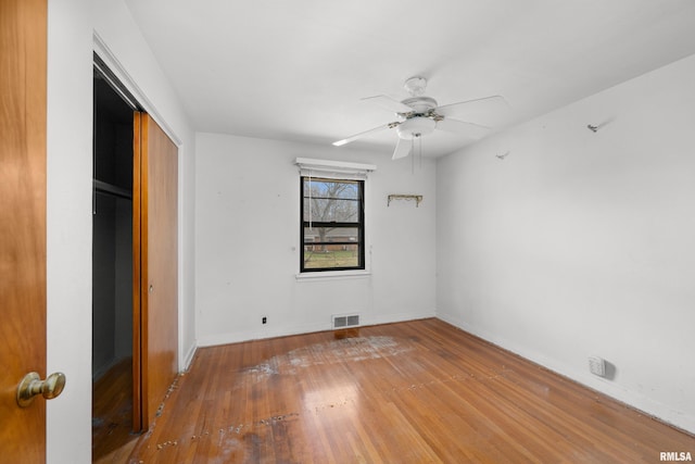 unfurnished bedroom with wood-type flooring, ceiling fan, and a closet