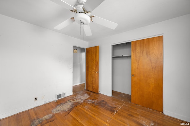 unfurnished bedroom with ceiling fan, dark hardwood / wood-style floors, and a closet