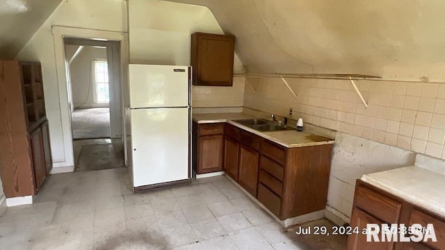 kitchen with lofted ceiling, sink, and white fridge