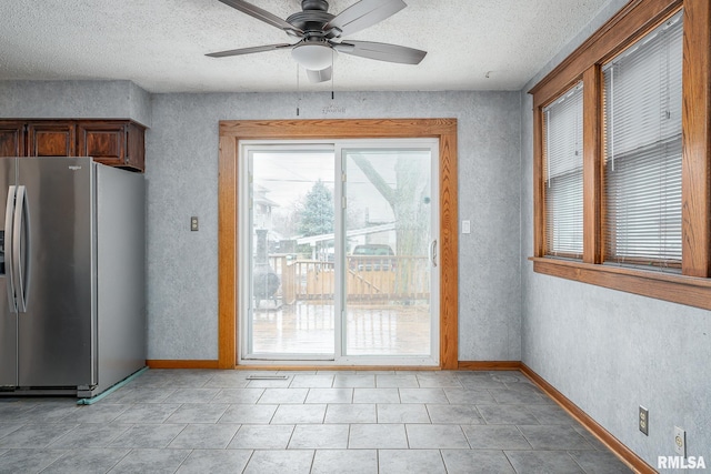 doorway with light tile patterned flooring, ceiling fan, and a textured ceiling