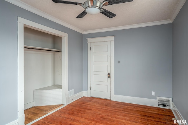 unfurnished bedroom with hardwood / wood-style flooring, ornamental molding, a closet, and a textured ceiling