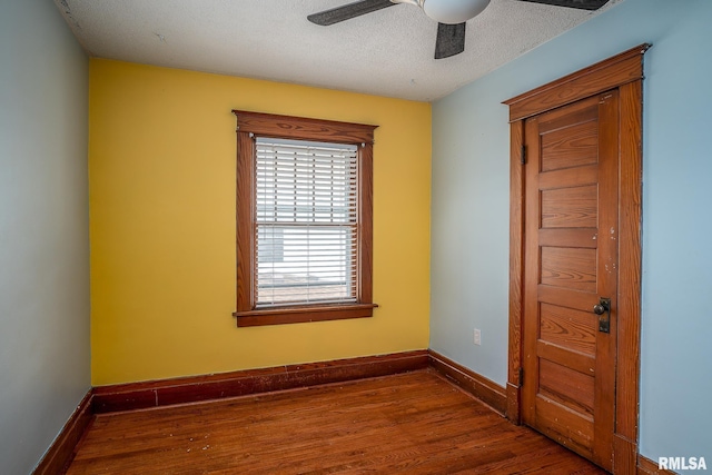 spare room featuring dark wood-type flooring, ceiling fan, and a textured ceiling