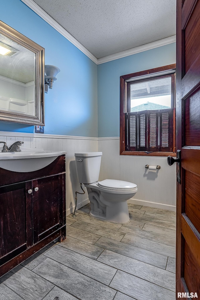 bathroom with crown molding, vanity, wood-type flooring, a textured ceiling, and toilet