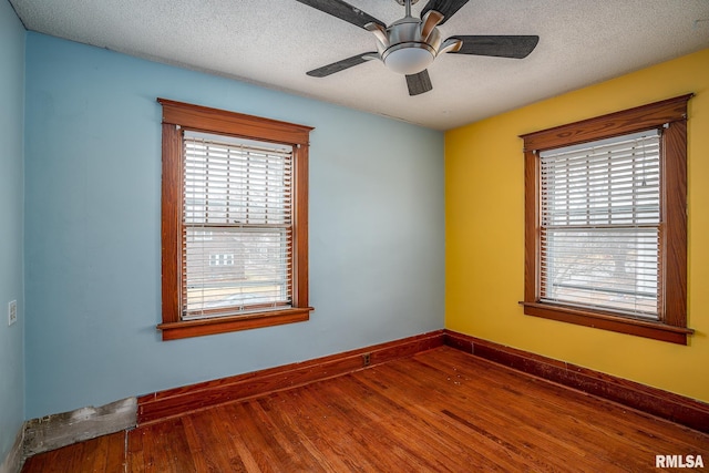 spare room featuring a healthy amount of sunlight, hardwood / wood-style floors, and a textured ceiling