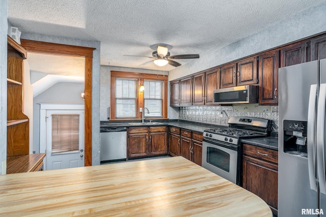 kitchen with sink, ceiling fan, stainless steel appliances, a textured ceiling, and wood counters