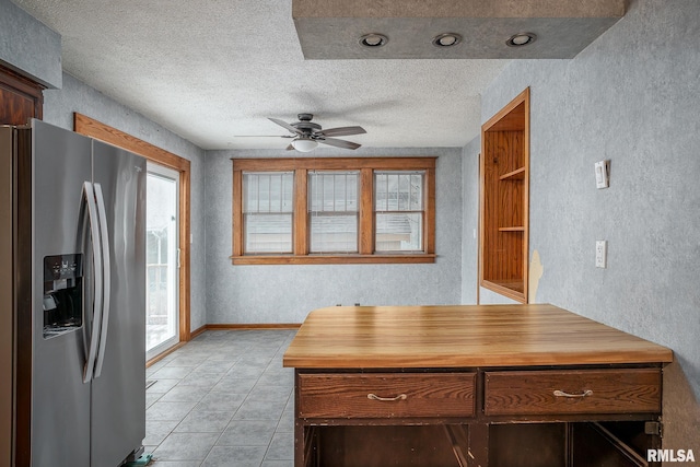 kitchen with light tile patterned flooring, wooden counters, ceiling fan, stainless steel fridge with ice dispenser, and a textured ceiling