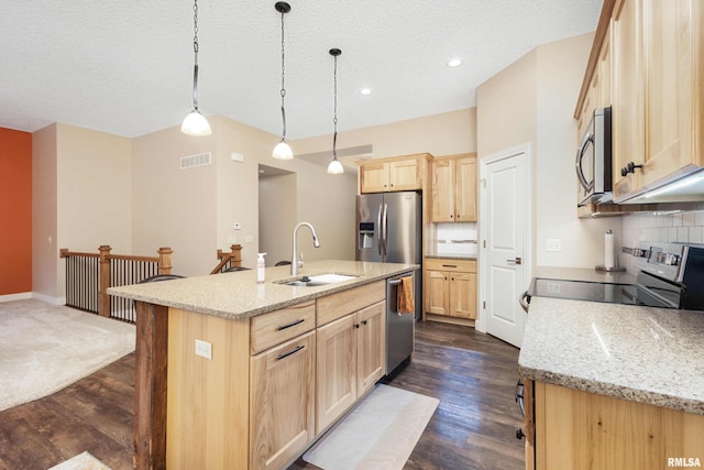 kitchen featuring pendant lighting, sink, a kitchen island with sink, stainless steel appliances, and light brown cabinets