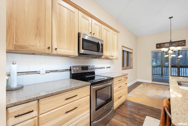 kitchen with light stone countertops, appliances with stainless steel finishes, light brown cabinets, and backsplash