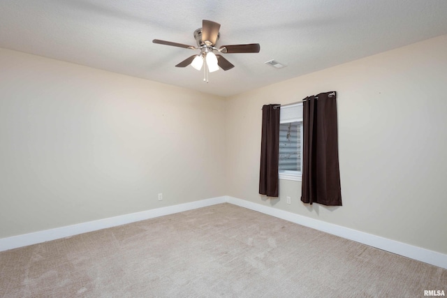 spare room with ceiling fan, light colored carpet, and a textured ceiling