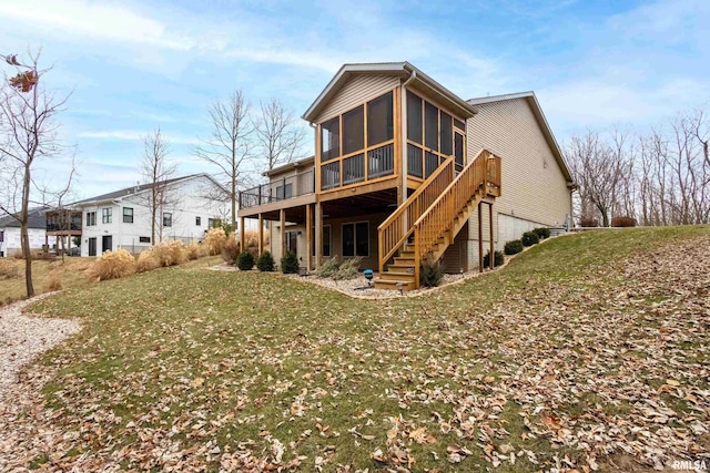 back of property with a wooden deck, a yard, and a sunroom