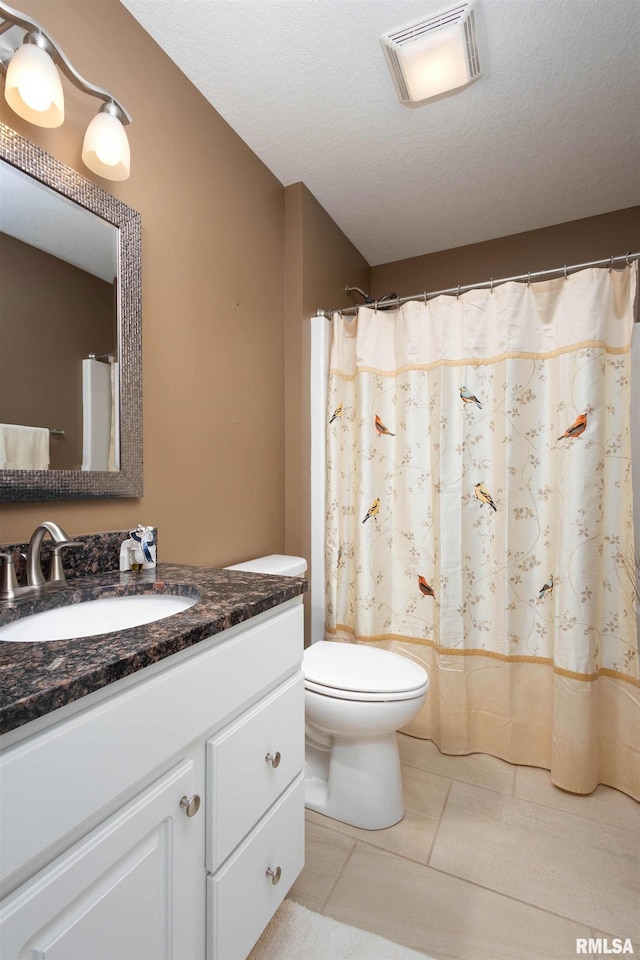 bathroom with tile patterned floors, toilet, vanity, and a textured ceiling