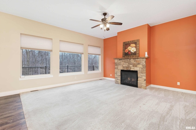 unfurnished living room featuring ceiling fan, a stone fireplace, and carpet