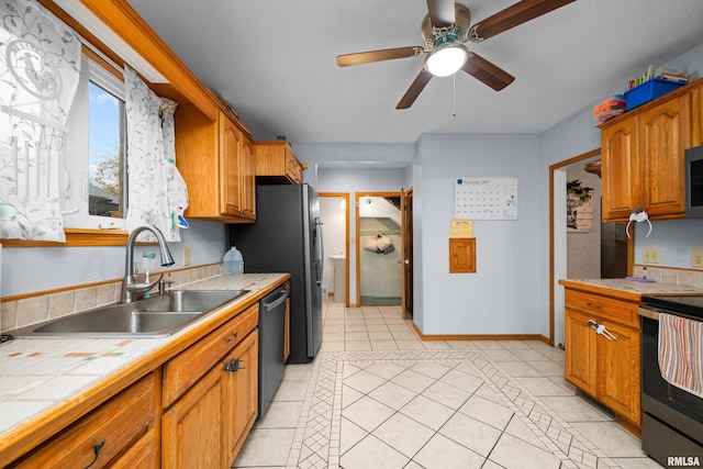 kitchen with sink, light tile patterned floors, tile counters, ceiling fan, and stainless steel appliances