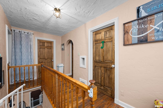 hall with hardwood / wood-style floors and a textured ceiling