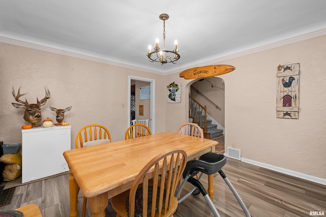 dining space featuring ornamental molding, hardwood / wood-style floors, and a chandelier