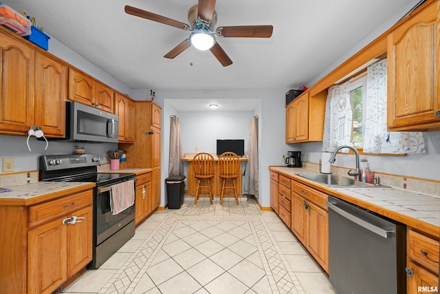 kitchen with light tile patterned flooring, stainless steel appliances, tile counters, and sink