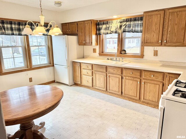 kitchen featuring an inviting chandelier, sink, white appliances, and hanging light fixtures