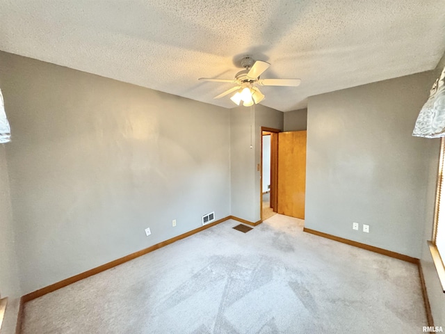 empty room with a textured ceiling, light colored carpet, and ceiling fan