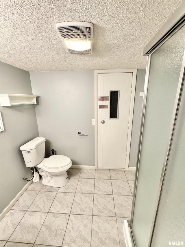 bathroom featuring an enclosed shower, toilet, and a textured ceiling