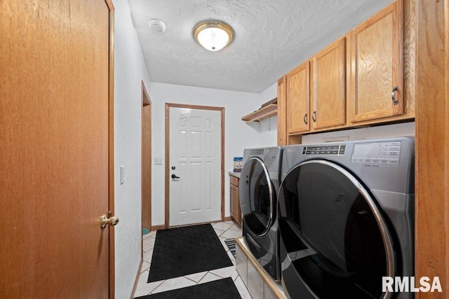 laundry area with light tile patterned floors, washing machine and dryer, cabinets, and a textured ceiling