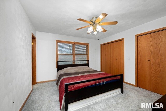 carpeted bedroom with ceiling fan and two closets