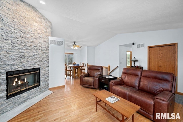 living room with lofted ceiling, a fireplace, and light hardwood / wood-style floors