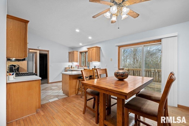 dining space with ceiling fan, light hardwood / wood-style floors, and vaulted ceiling