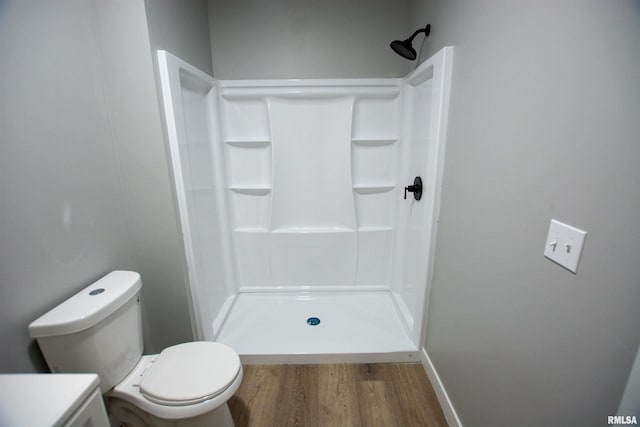 bathroom with hardwood / wood-style flooring, toilet, and a shower