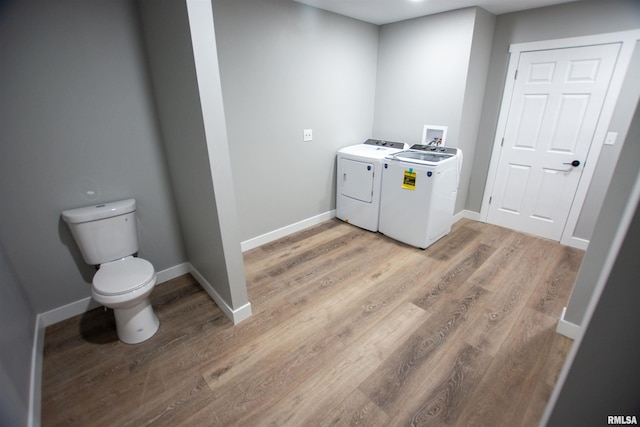 laundry room with separate washer and dryer and light hardwood / wood-style floors